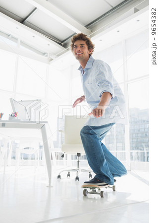 Happy young man skateboarding in office 9654382