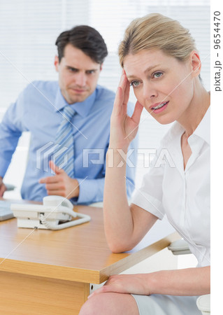 Upset businesswoman with man working on laptop 9654470