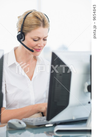 Female executive with headset using computer at desk 9654843