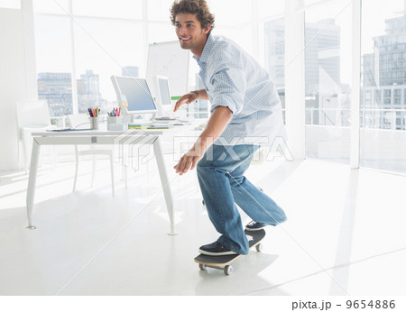Happy young man skateboarding in office 9654886