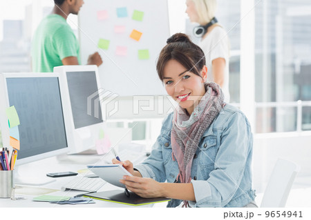Artist drawing something on graphic tablet with colleagues behin Artist drawing something on graphic tablet with colleagues behin 9654941