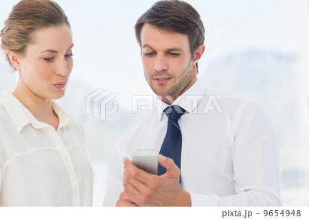 Smartly dressed colleagues looking at mobile phone 9654948