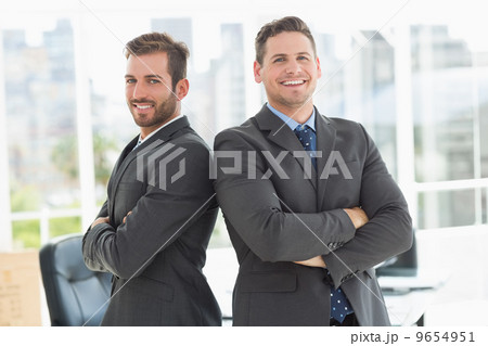 Businessmen standing with arms crossed in office Businessmen standing with arms crossed in office 9654951