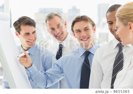 Young businessman writing on whiteboard with colleagues Young businessman writing on whiteboard with colleagues 9655365