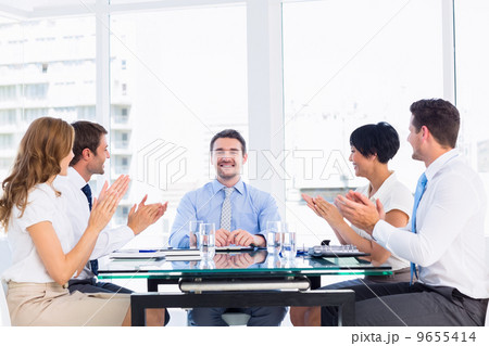 Executives clapping around conference table Executives clapping around conference table 9655414