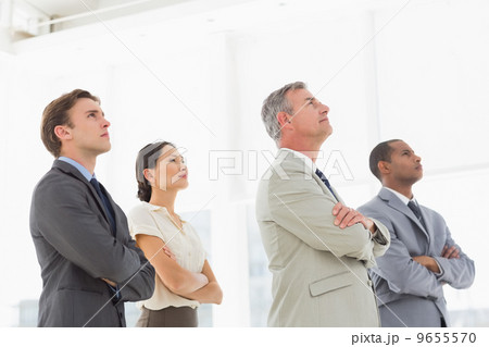 Serious business team with arms folded looking up 9655570