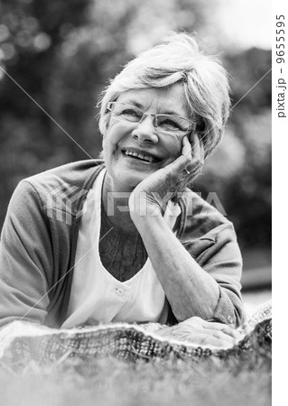 Smiling senior woman lying at park 9655595