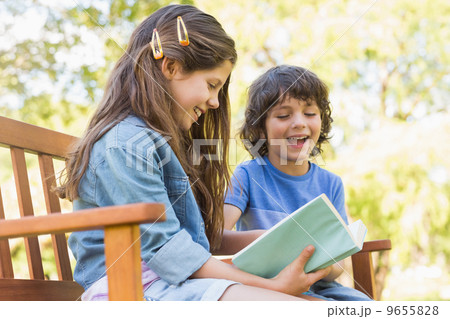 Side view of kids reading book on park bench Side view of kids reading book on park bench 9655828