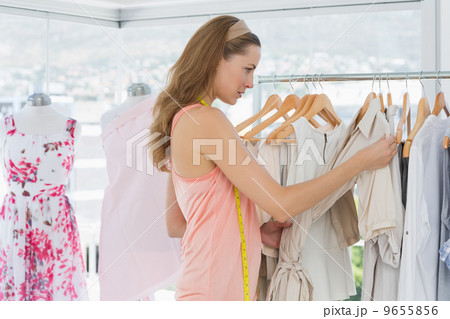 Beautiful fashion designer looking at clothes on rack 9655856