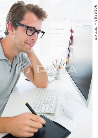 Side view of a casual male photo editor using graphics tablet 9656166