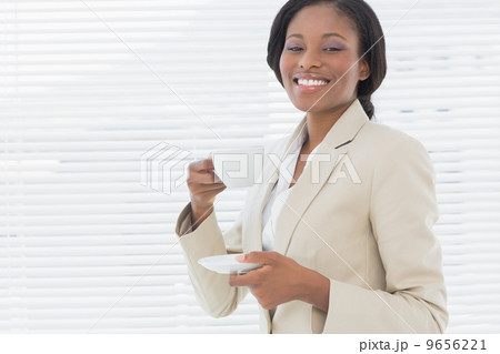 Elegant smiling businesswoman with a cup of tea in office Elegant smiling businesswoman with a cup of tea in office 9656221