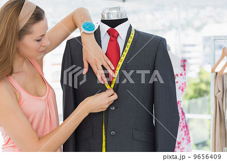 Female fashion designer measuring suit on dummy Female fashion designer measuring suit on dummy 9656409