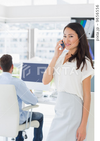 Female artist using mobile phone with colleague in background 9656556