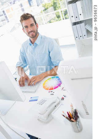 Smiling male photo editor using computer 9656673
