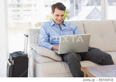 Travelling businessman using laptop sitting on the couch Travelling businessman using laptop sitting on the couch 9656858
