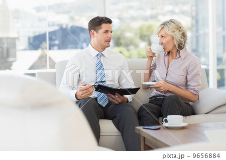 Smart businessman and his secretary with diary and tea cup Smart businessman and his secretary with diary and tea cup 9656884