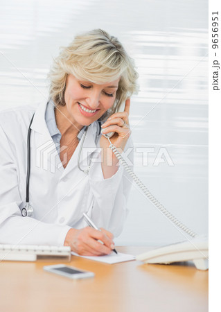 Doctor using phone while writing notes at medical office Doctor using phone while writing notes at medical office 9656951