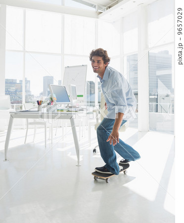 Happy man skateboarding in a bright office 9657029