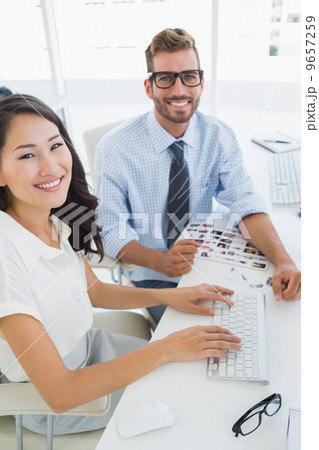 Side view of casual photo editors working on computer 9657259