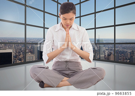 Composite image of businesswoman sitting in lotus pose 9663855