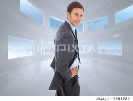 Composite image of cheerful businessman standing with hands on h 9663927