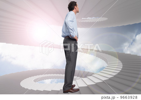 Composite image of serious businessman with hand on hip 9663928