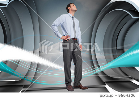 Composite image of serious businessman with hand on hip 9664306