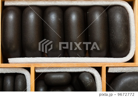 Black spa zen massage stones in wooden case as background 9672772