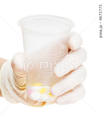 gloved hand holding plastic cup with pills 9675775
