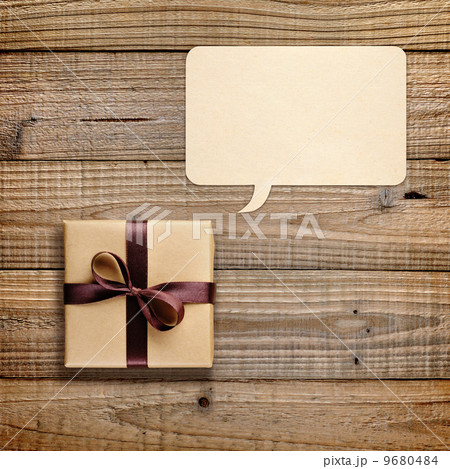 Gift box and speech bubble on wooden background 9680484