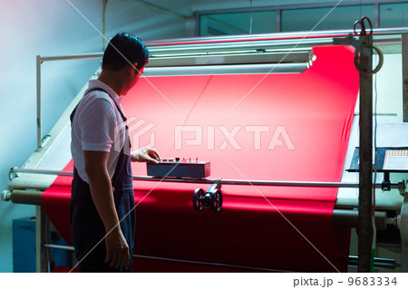Asian worker controls fabrics in textile plant 9683334