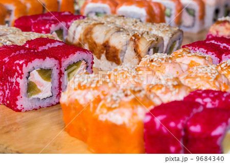 assorted sushi and rolls on wood board in dark light 9684340