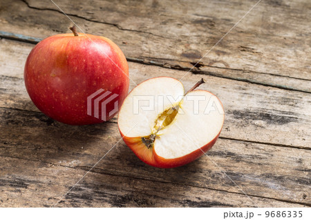 Whole and Cut in Half Apple lying on Textured Weathered Wooden Table 9686335