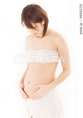 少し膨らんだお腹を大切そうに抱えて嬉しそうに笑う妊婦さんの写真素材