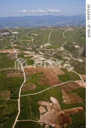Aerial view at farm fields in front of misty mountains 9689546