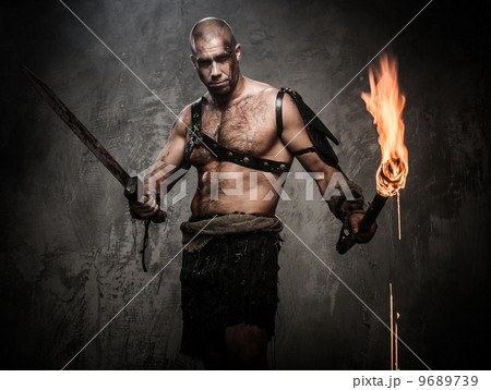 Wounded gladiator holding torch and sword covered in blood 9689739