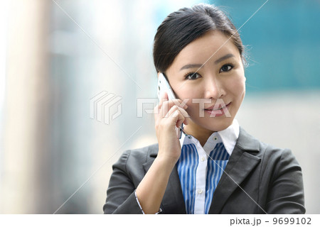 Business woman outdoor using mobile phone in front of glass building shallow depth of field 9699102
