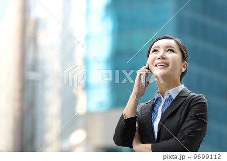 Business woman outdoor using mobile phone in front of glass building shallow depth of field 9699112