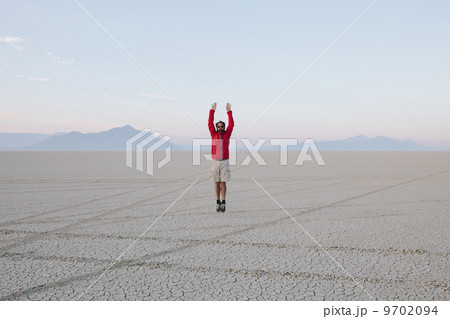 A man jumping in the air on the flat desert or playa or Black Rock Desert, Nevada. 9702094