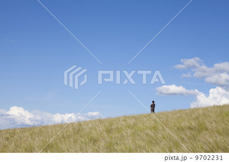A man standing on the crest of a hill. 9702231