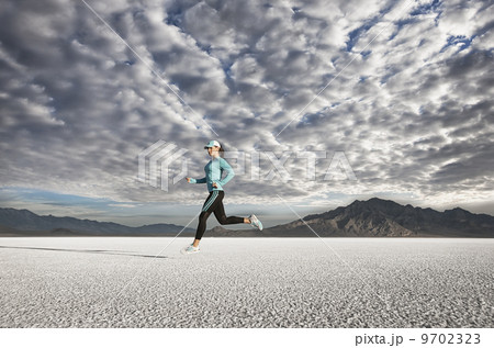 A young woman running through the landscape on the salt flats surface near Salt Lake city. A young woman running through the landscape on the salt flats surface near Salt Lake city. 9702323