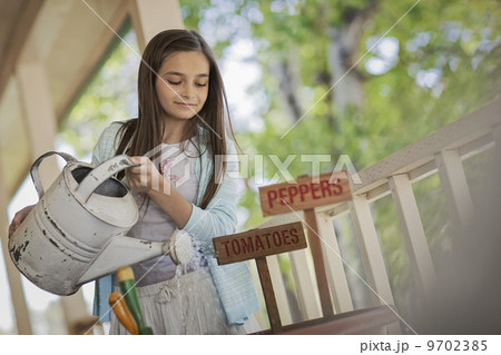 A child holding a watering can, watering a a pot with newly planted tomato and pepper seeds. A child holding a watering can, watering a a pot with newly planted tomato and pepper seeds. 9702385