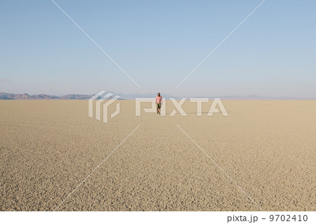 Man walking across a flat desert landscape 9702410