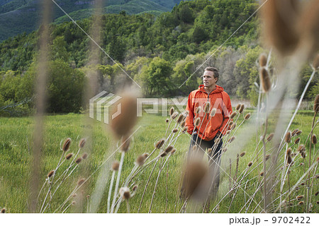 A man in an orange jacket walking his property. 9702422