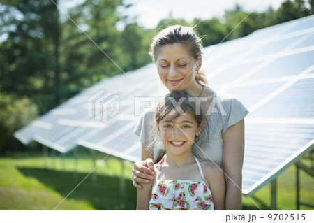 A child and her mother in the fresh open air, beside solar panels on a sunny day at a farm in New York State, USA. 9702515