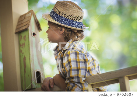 A child examining a bug box on a porch. 9702607