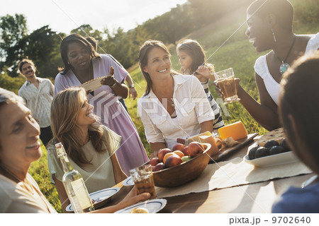 A family and friends having a meal outdoors. A picnic or buffet in the early evening. A family and friends having a meal outdoors. A picnic or buffet in the early evening. 9702640
