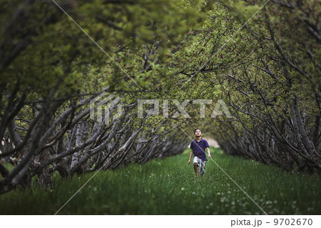 A child running along a natural woodland tunnel with tree branches forming an arch. 9702670