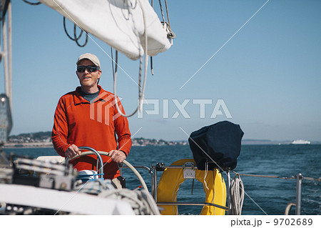 Middle aged man steering sailboat on Puget Sound, Washington, USA Middle aged man steering sailboat on Puget Sound, Washington, USA 9702689