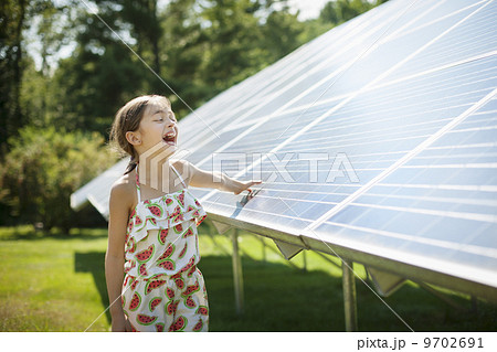 A child in the fresh open air on a sunny day, beside solar panels at a farm in New York State, USA. 9702691